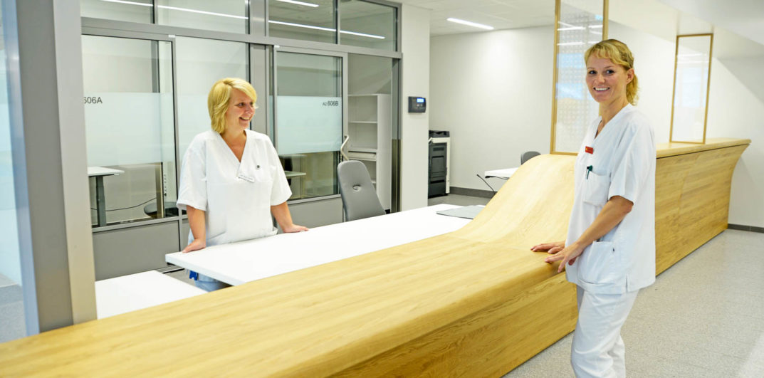 Et par kvinner i hvite laboratoriefrakker som står ved et bord