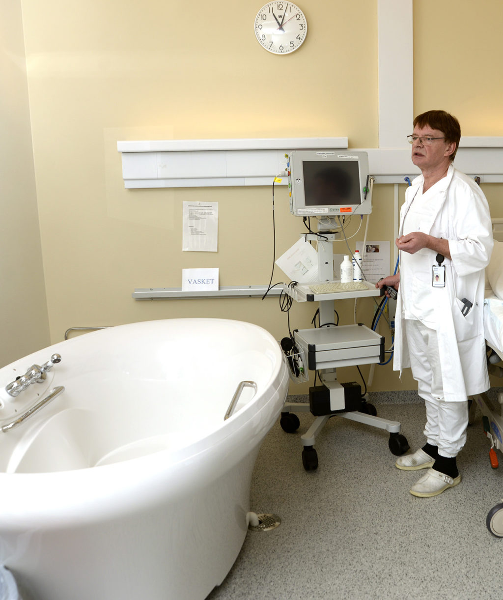 En mann i hvit frakk på et sykehusrom