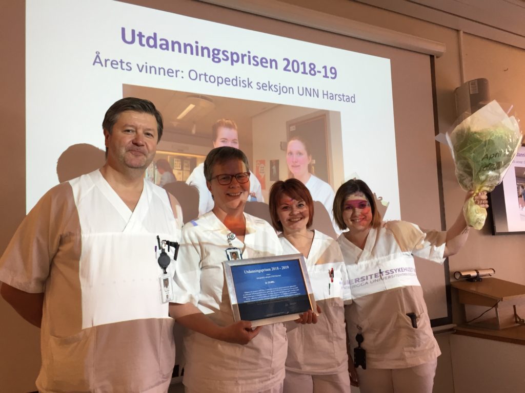 En gruppe mennesker i hvite laboratoriefrakker som holder en bærbar PC