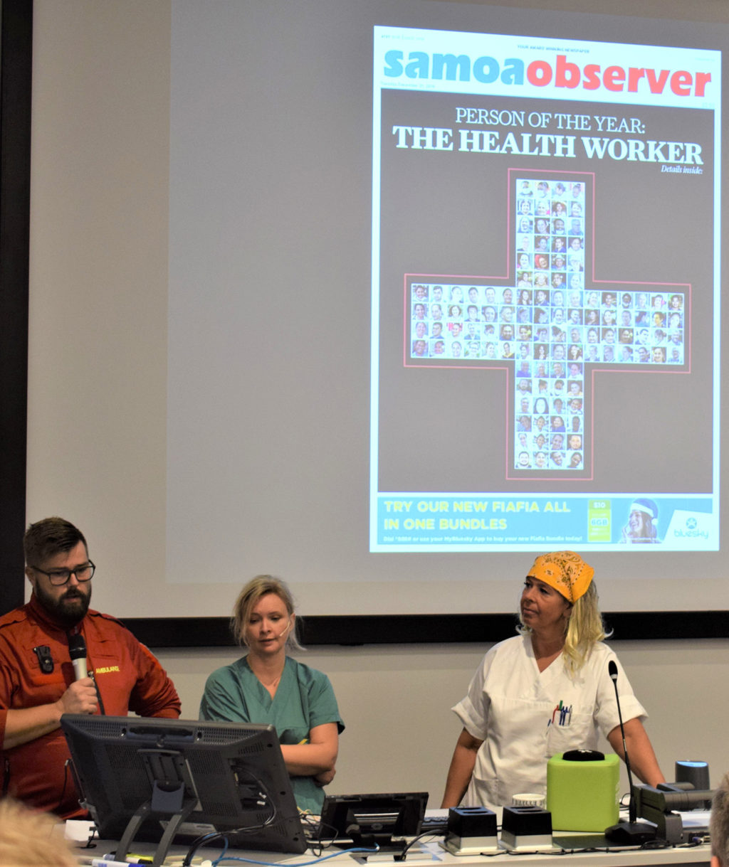 En gruppe mennesker som sitter ved et bord med bærbare datamaskiner og en projektorskjerm