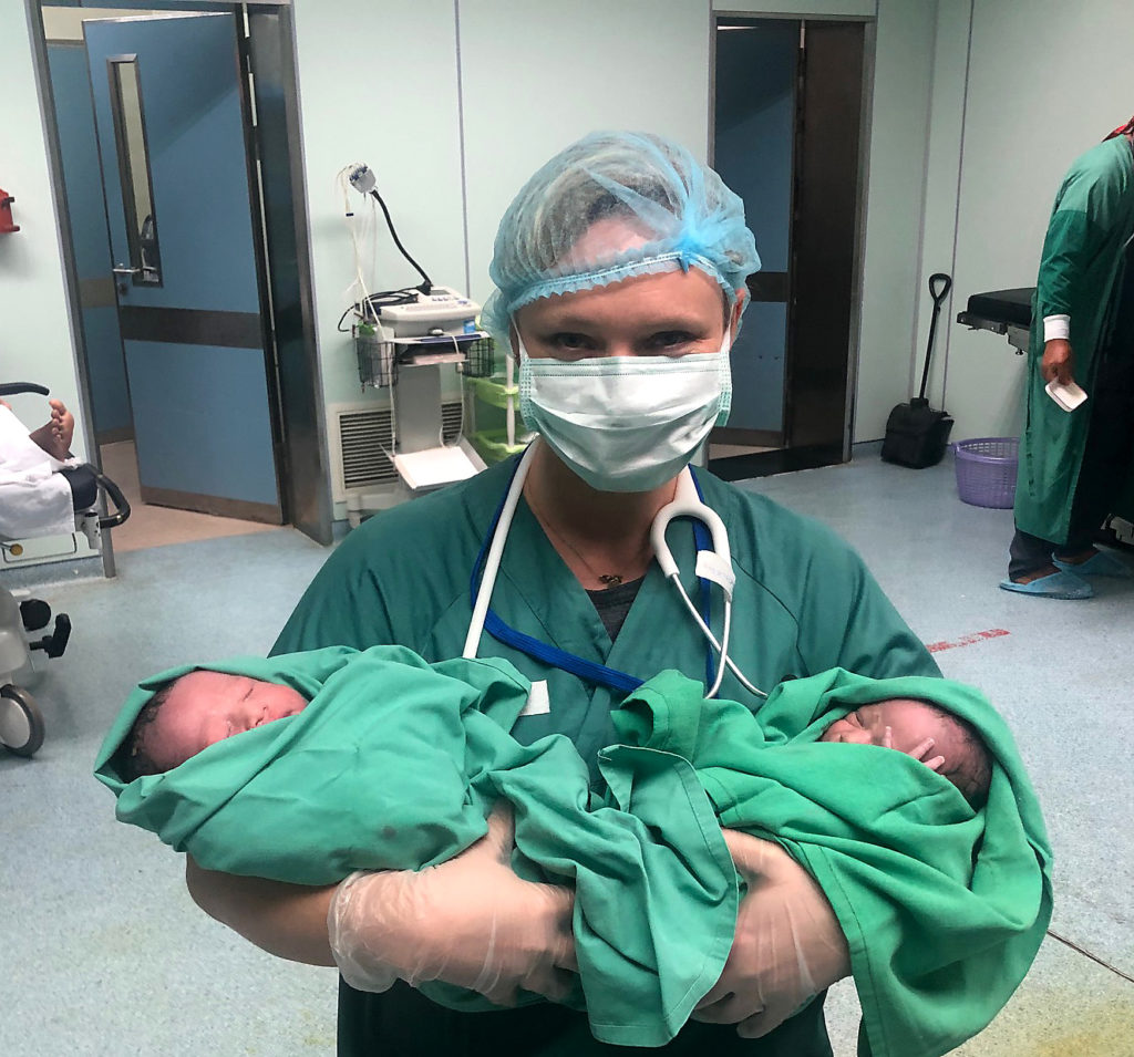 En person i kirurgisk uniform som holder en baby