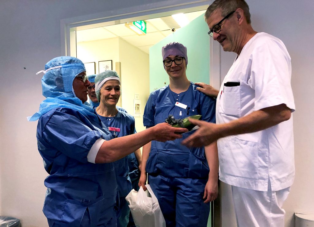 En gruppe mennesker i kirurgiske uniformer som ser på en enhet