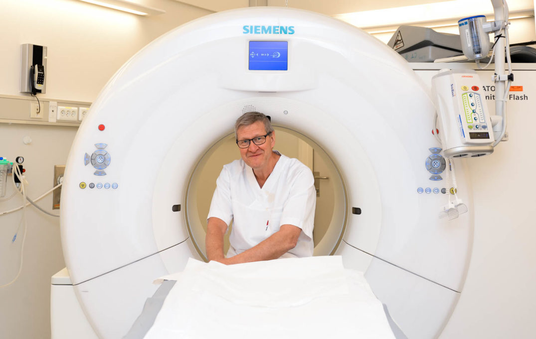 En mann i hvit skjorte i et hvitt rom med en hvit maskin