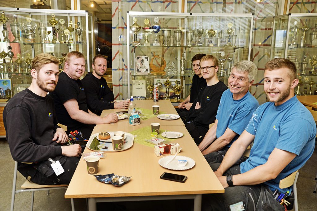 En gruppe menn som sitter ved et bord med mat