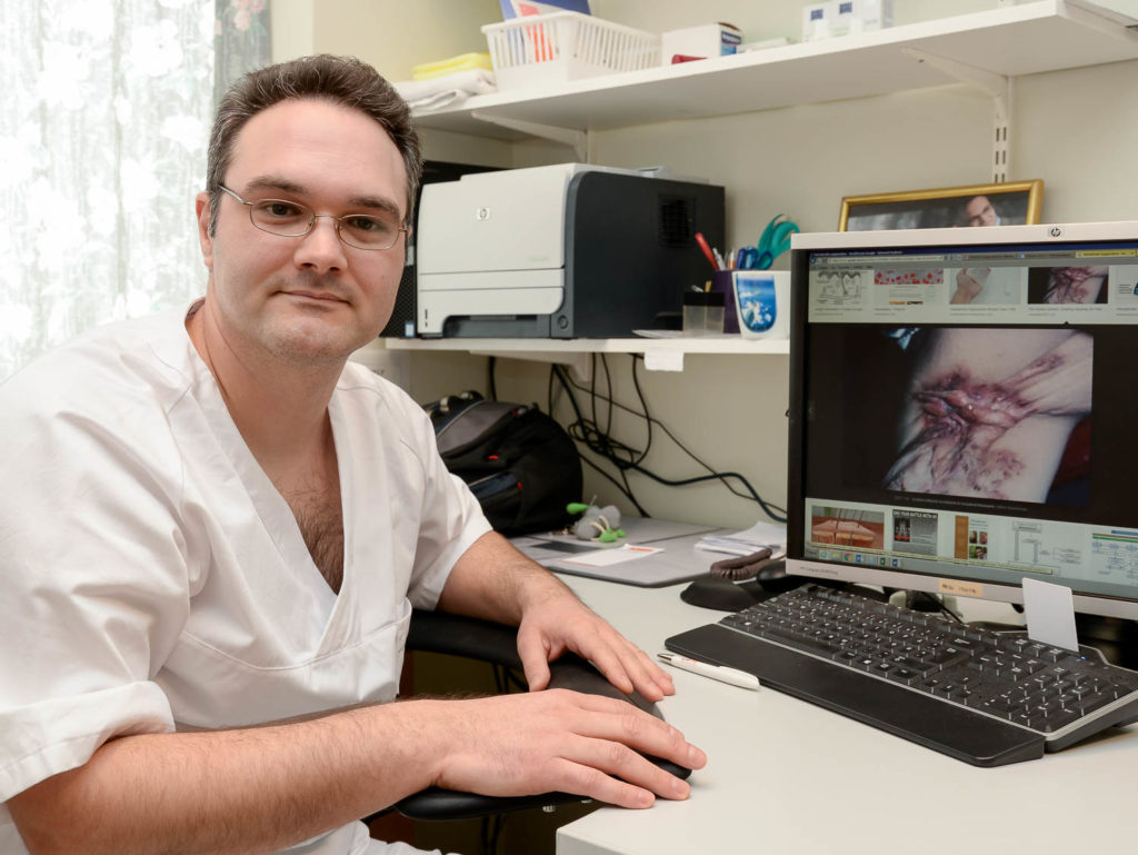 En mann som sitter ved et skrivebord med en datamaskin