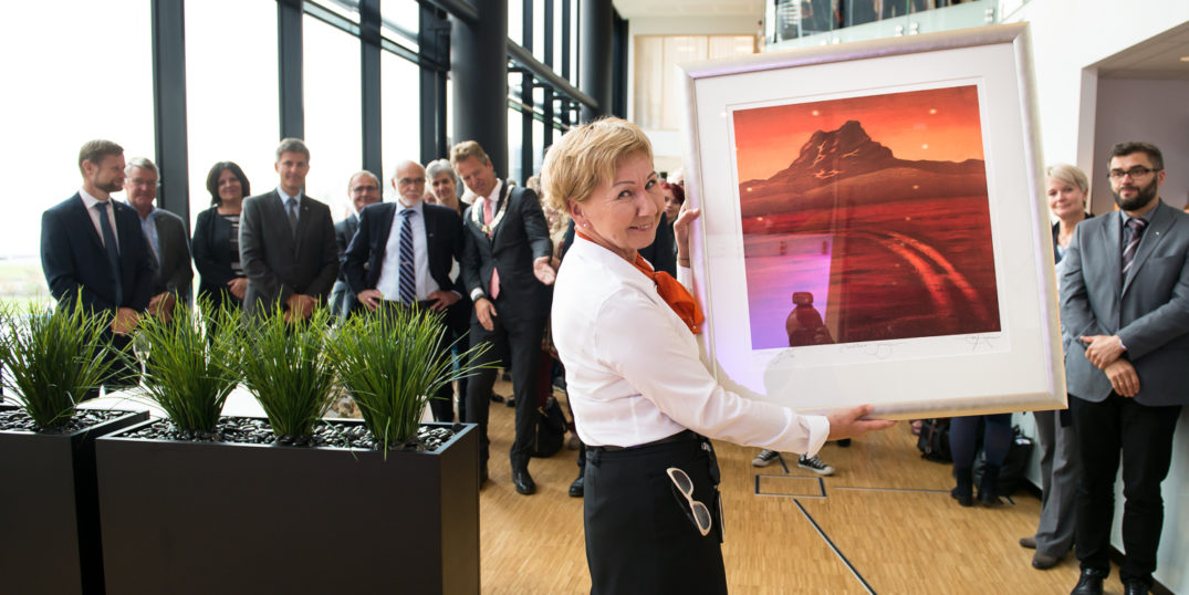 En person som står foran en skjerm med folk i bakgrunnen