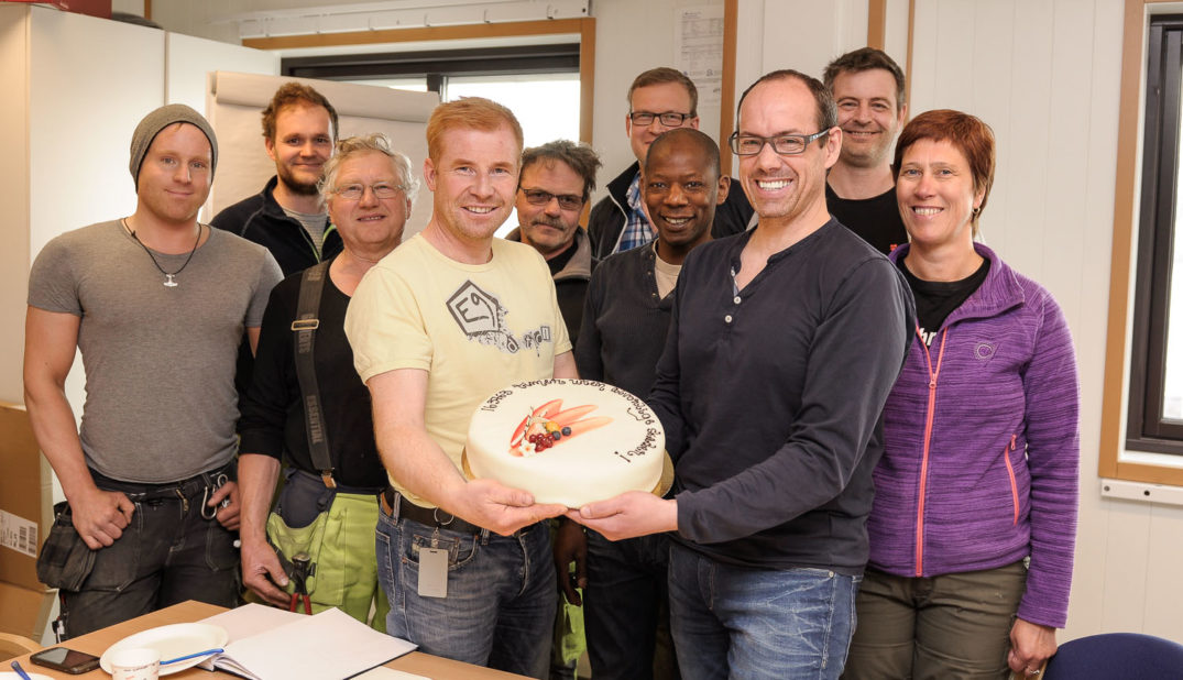 En gruppe mennesker som poserer for et bilde med en kake