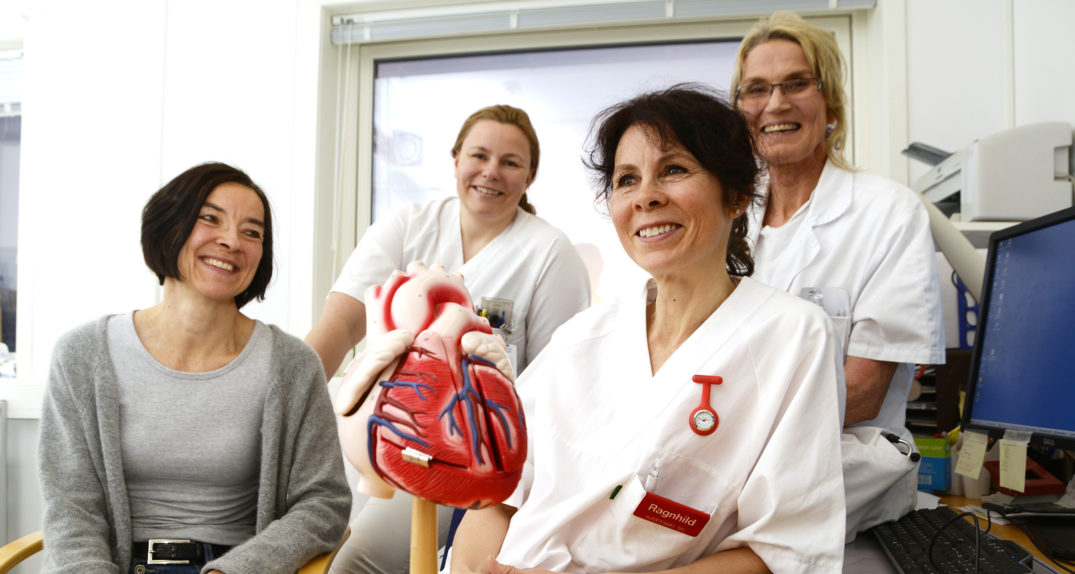 En gruppe kvinner i hvite laboratoriefrakker som holder en baby