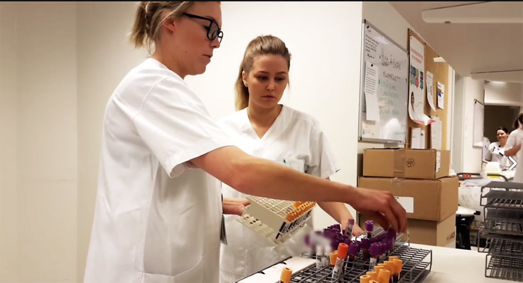 En kvinne og en mann i laboratoriefrakk som ser på en pakke