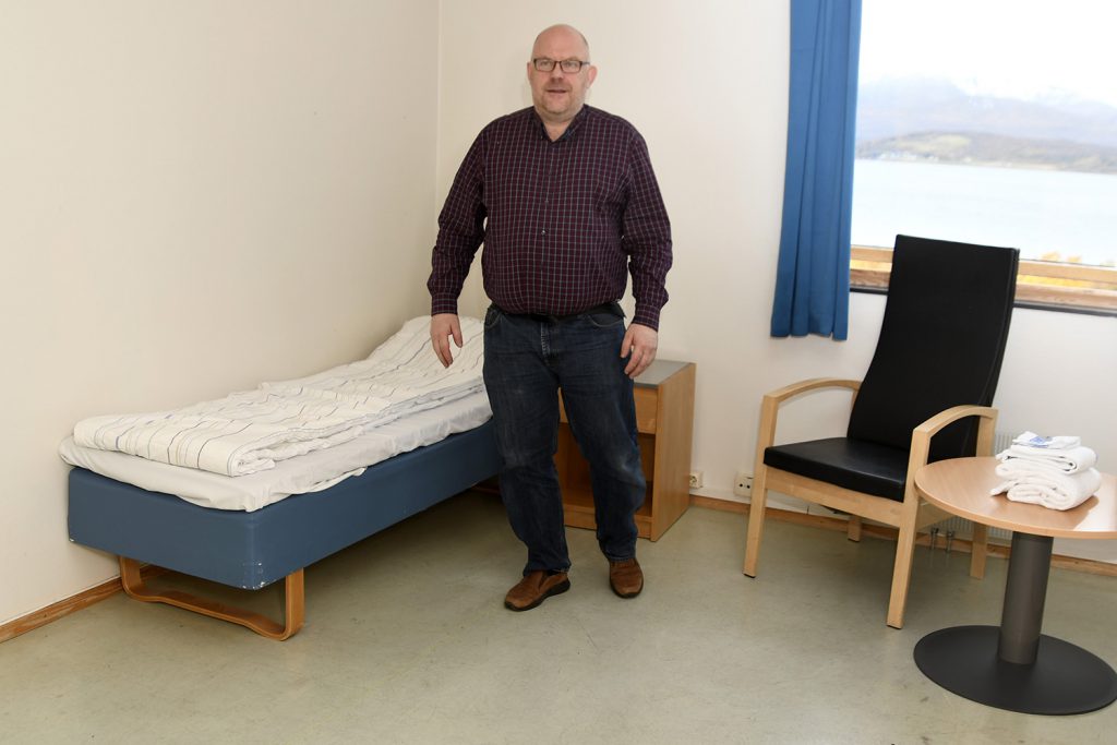 En mann som står ved siden av en seng