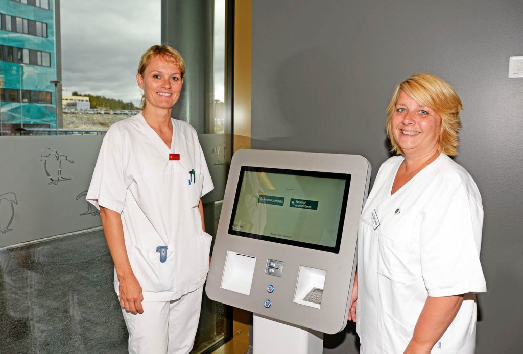 Et par kvinner i hvite frakker som står ved siden av en datamaskin