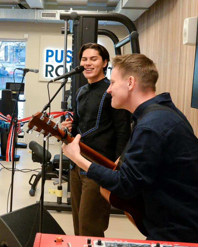 En mann som spiller gitar ved siden av en mann som spiller et musikkinstrument