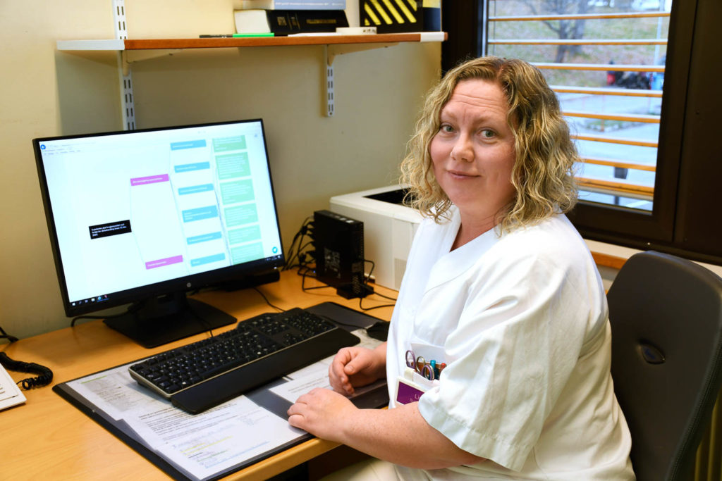 En person som sitter ved et skrivebord med en datamaskin