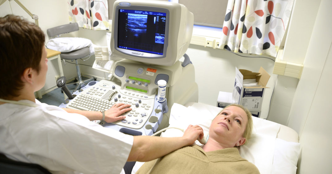 En lege som viser en pasient noe på datamaskinen