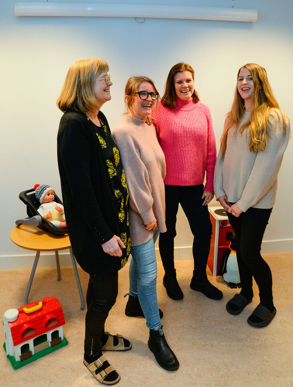 Fire personer som smiler og ler, leker på gulv og bak dem