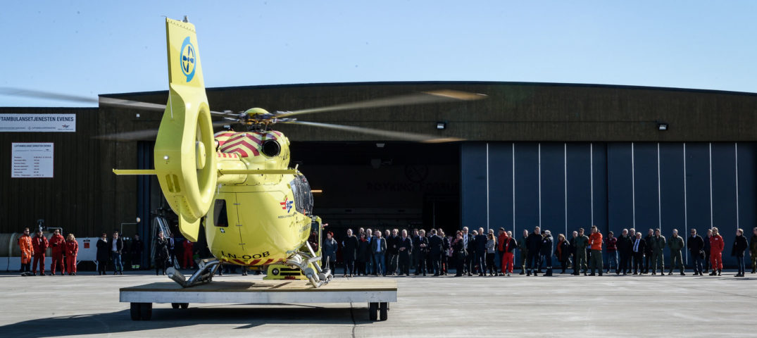 En gruppe mennesker som står ved siden av et helikopter