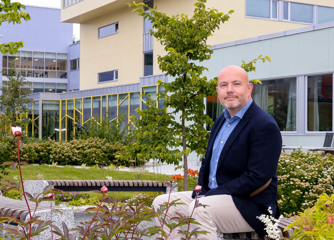 En mann som sitter på en stol utenfor