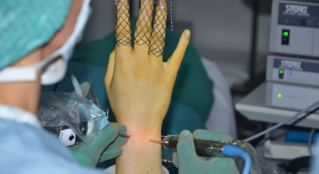 En person med maske som holder en nål