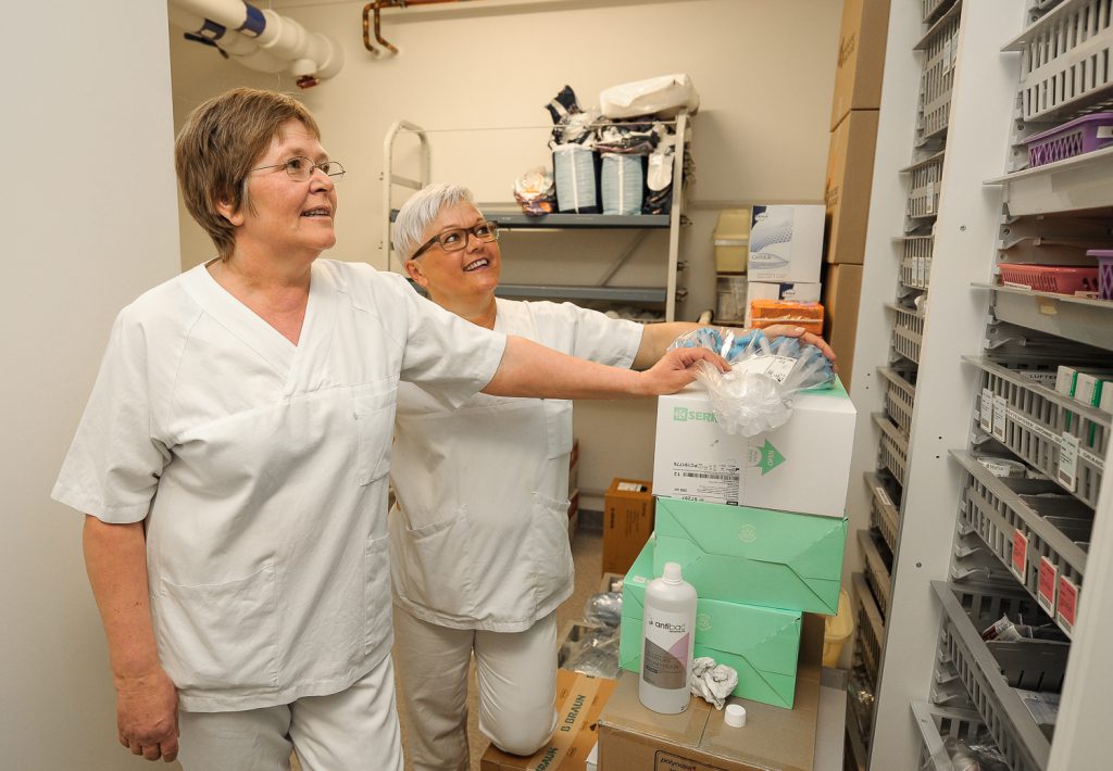 Et par menn i hvite laboratoriefrakker i et rom med hyller