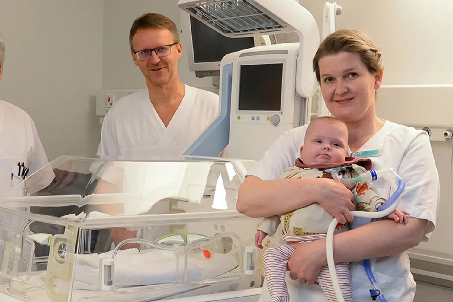 En gruppe mennesker i hvite laboratoriefrakker som holder en baby