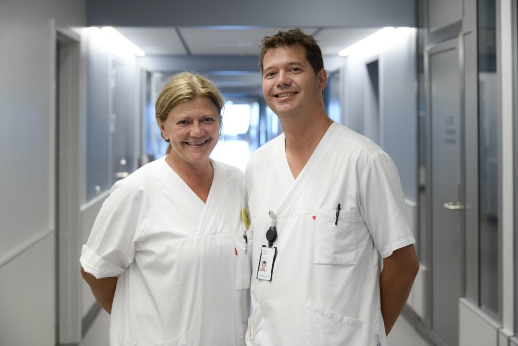 En mann og en kvinne i hvite skjorter står i et rom