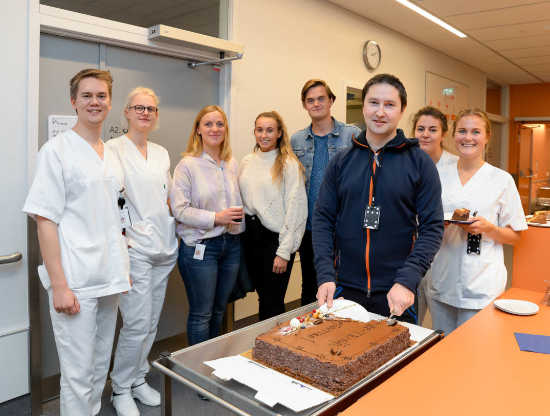 En gruppe mennesker som står rundt en kake