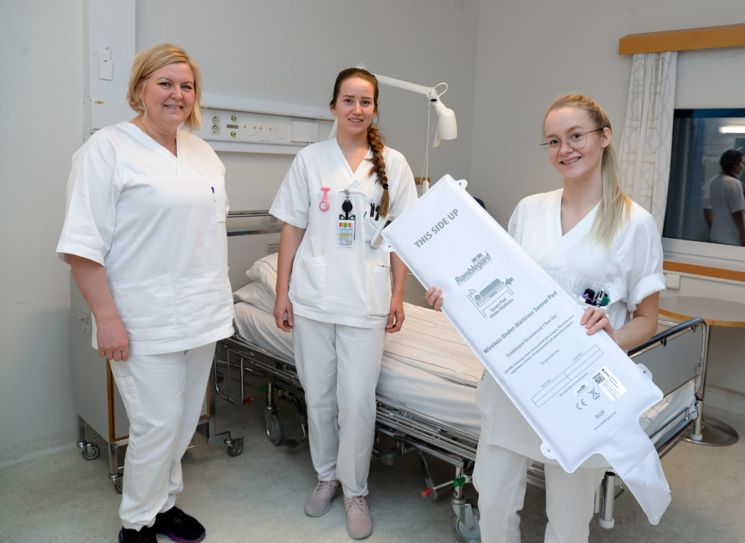 En gruppe kvinner i hvite laboratoriefrakker som holder et stort hvitt røntgenbilde