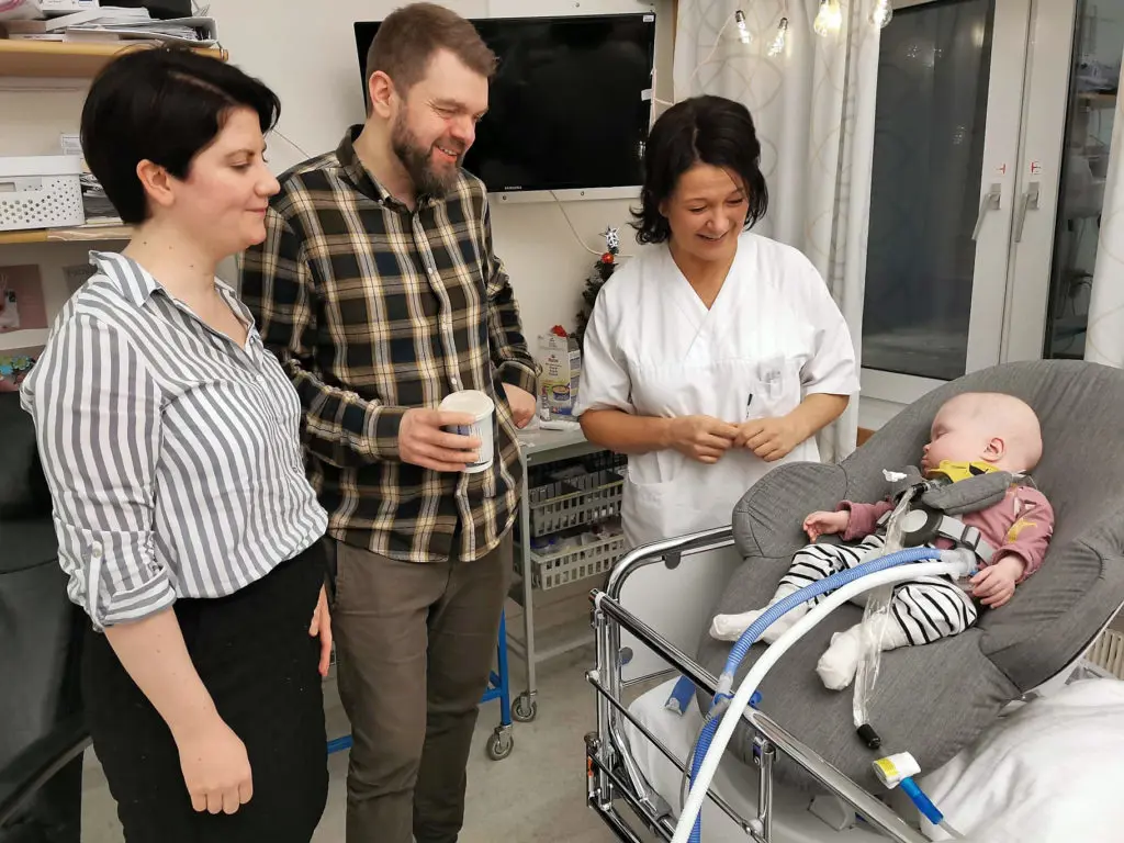 En gruppe mennesker som står rundt en baby i en sykehusseng