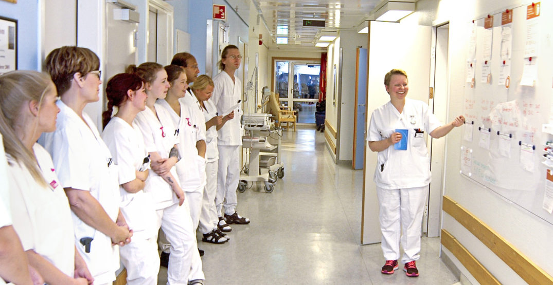 En gruppe mennesker i hvite laboratoriefrakker som ser på en whiteboard