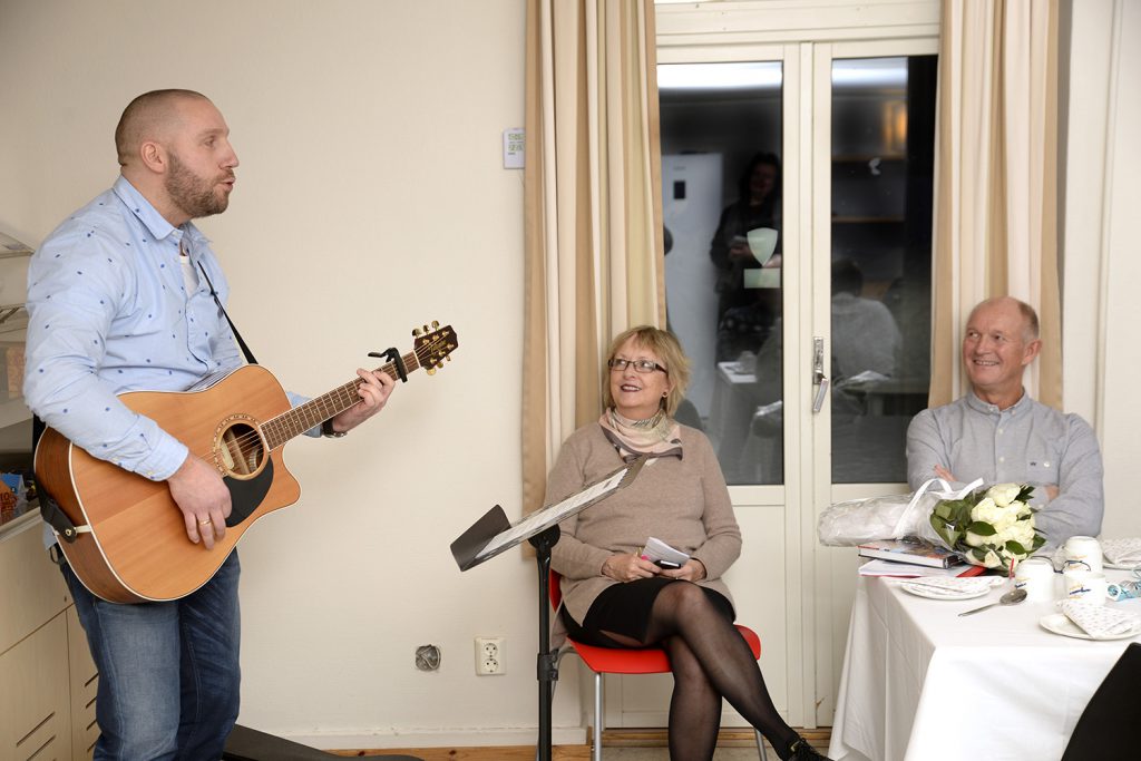 En mann som spiller gitar foran en gruppe mennesker