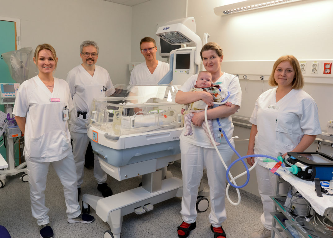 En gruppe mennesker i hvite laboratoriefrakker står foran en maskin