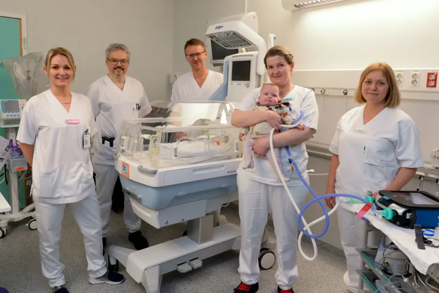 En gruppe mennesker i hvite laboratoriefrakker står foran en maskin