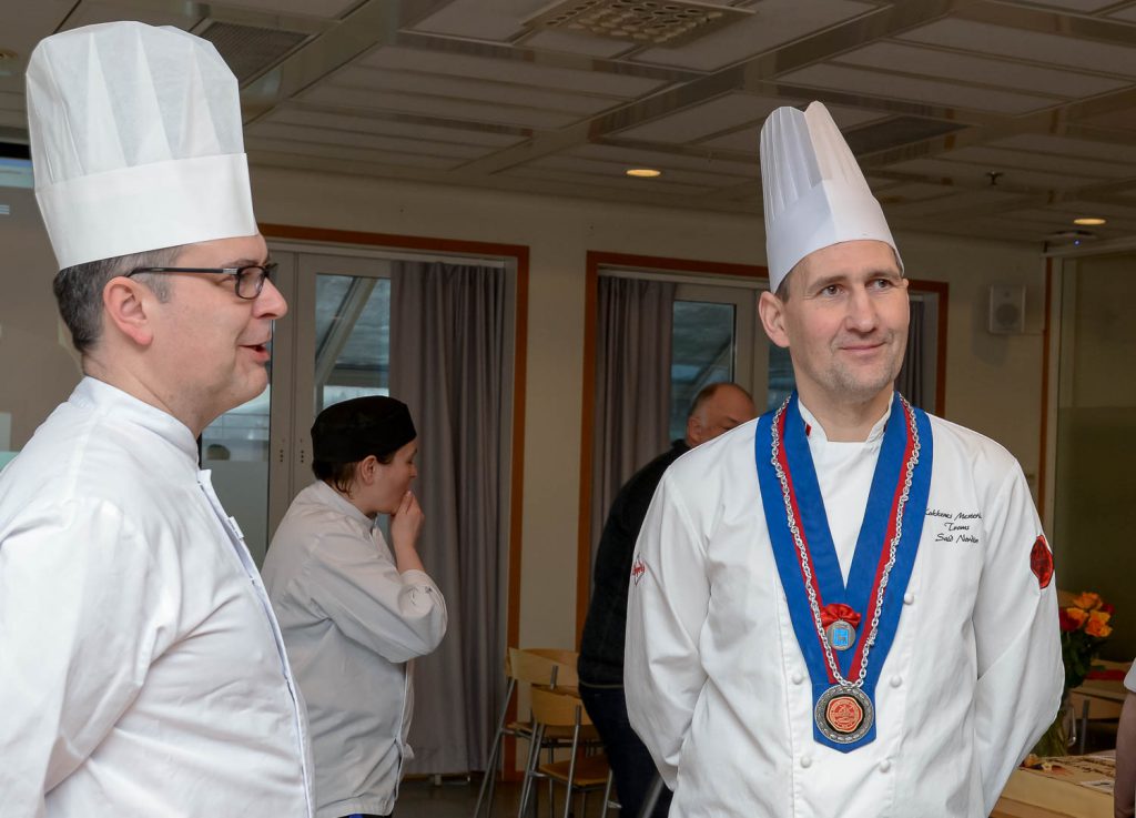 En person med kokkelue og en person i kokkeuniform