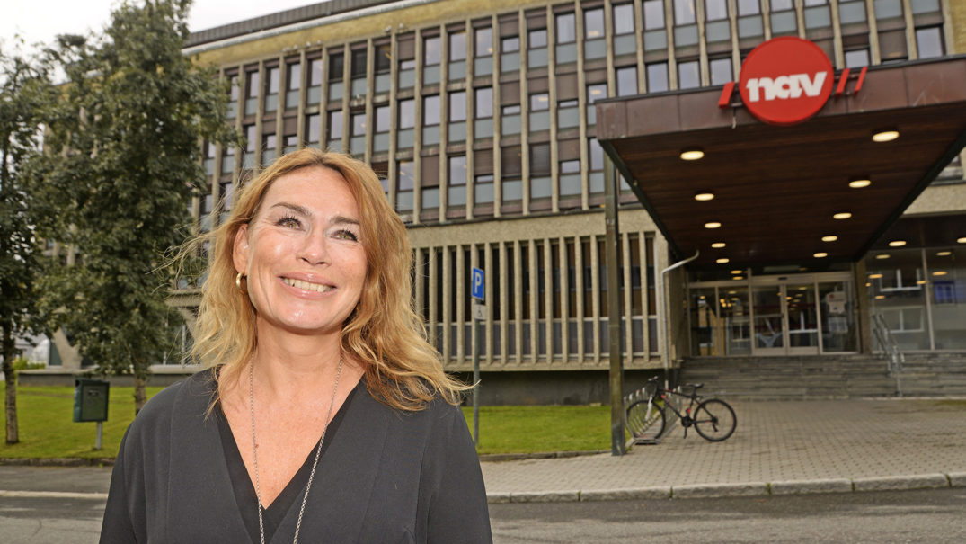 En person som smiler foran en bygning