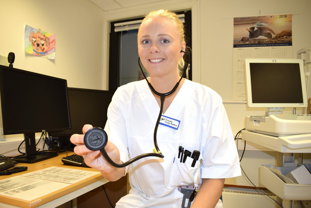 En person iført hvit frakk og holder en svart gjenstand