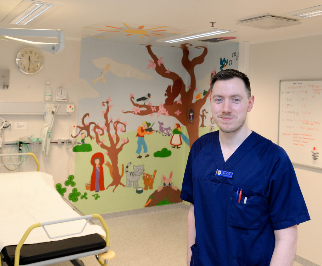 En person som står foran en vegg med kunst på