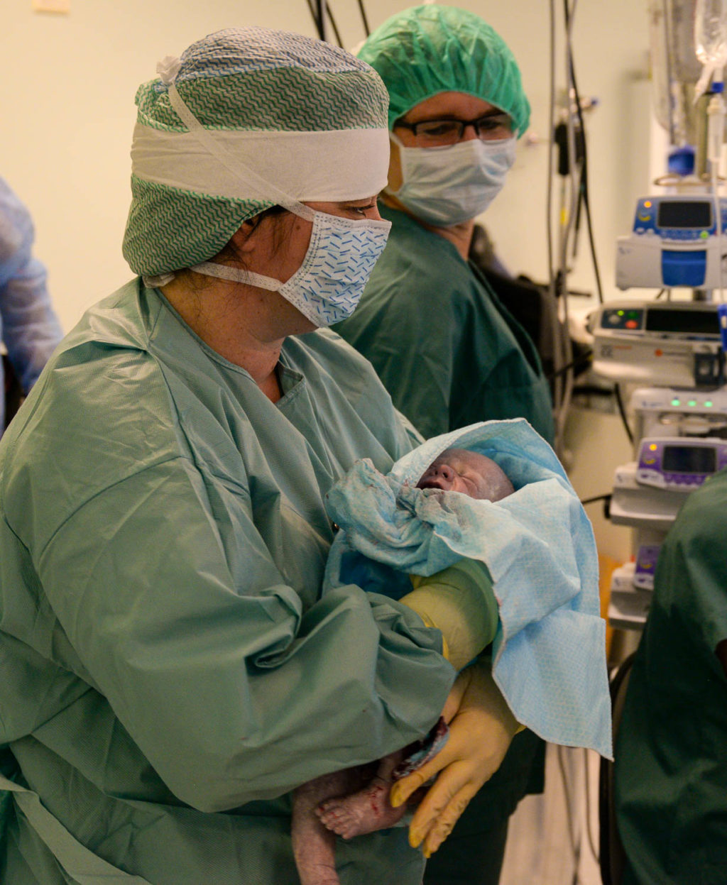 En person i kirurgisk uniform som holder en baby