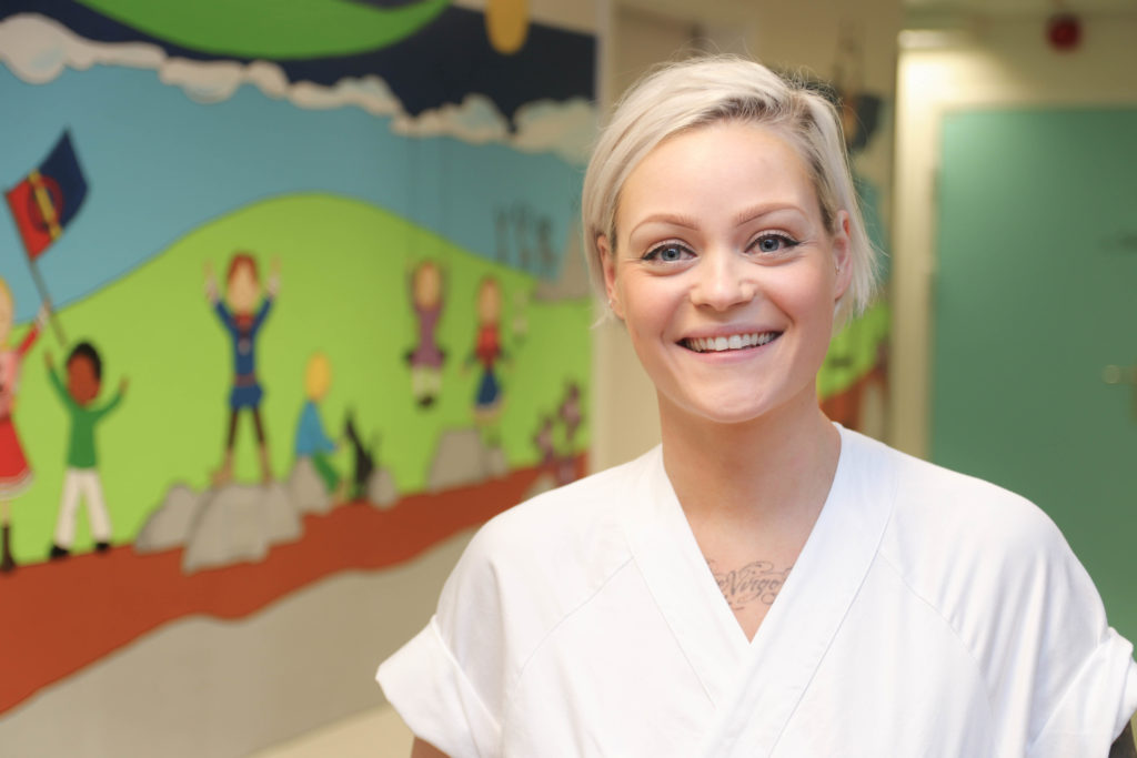 En person som smiler foran et maleri