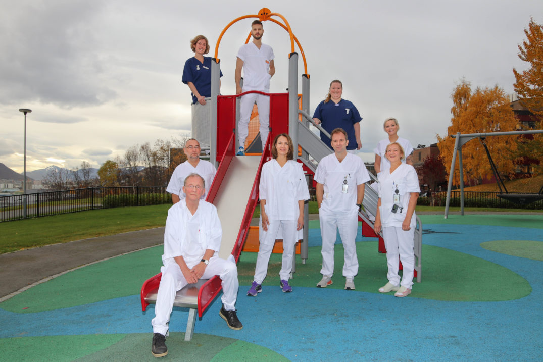 En gruppe mennesker som poserer for et bilde foran en rød bygning