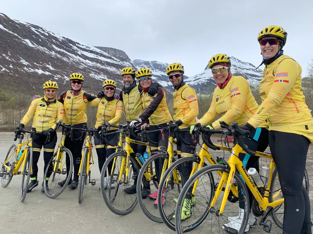 En gruppe mennesker iført gule jakker og stående ved siden av sykler