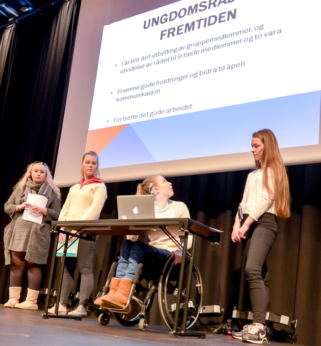 En gruppe mennesker som står rundt en kvinne i rullestol