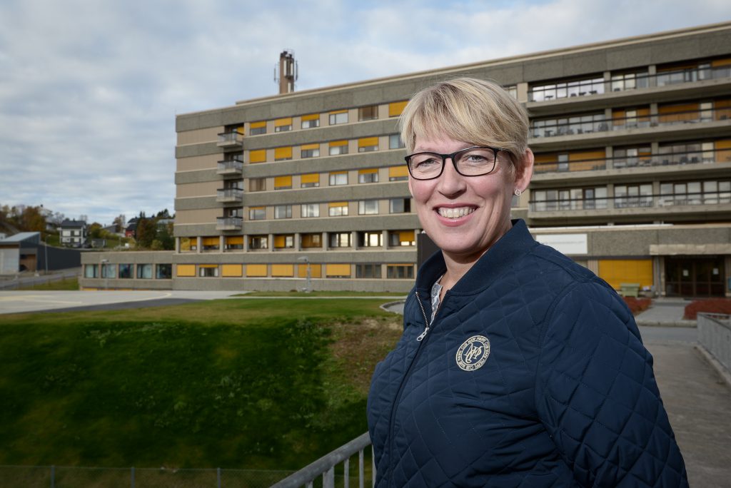 En mann som smiler foran en bygning