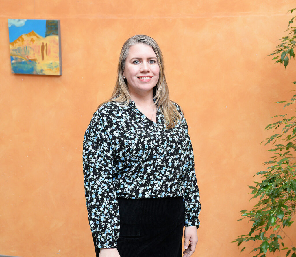 En kvinne som står foran en vegg med kunst på.