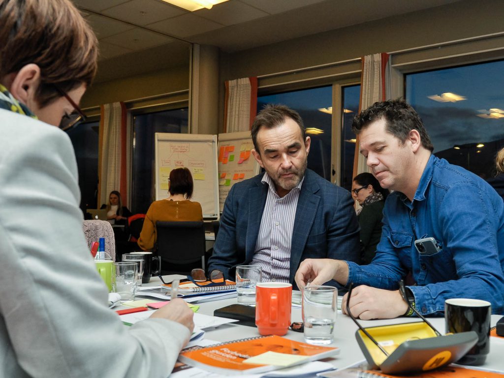 En gruppe mennesker som sitter ved et bord og ser på et papir