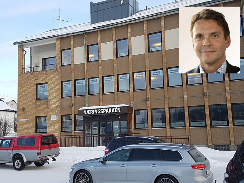 En person som står foran en bygning med biler parkert foran