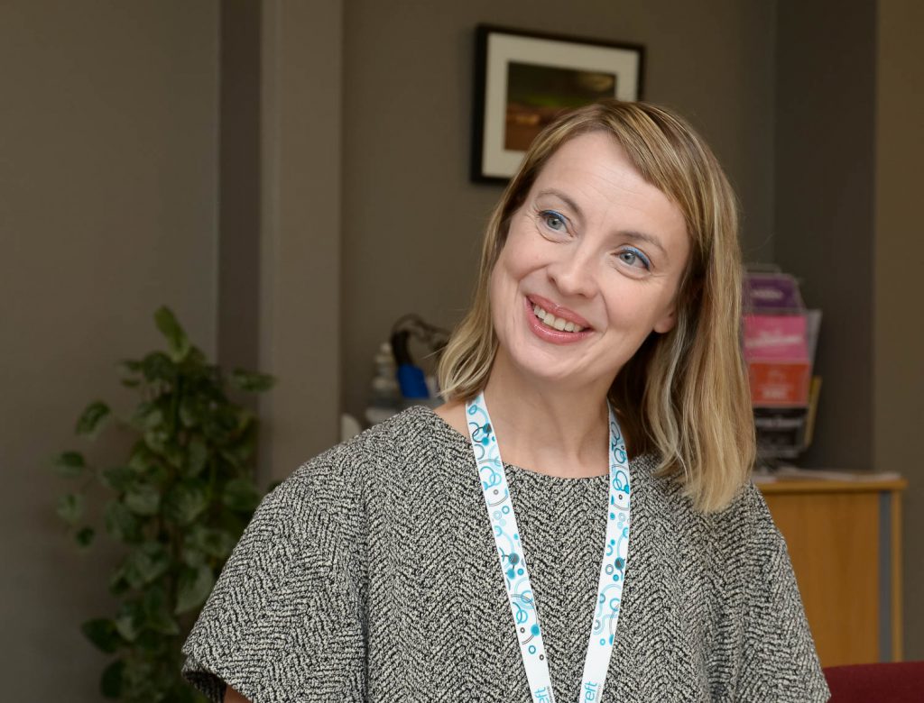 En kvinne som smiler til kameraet