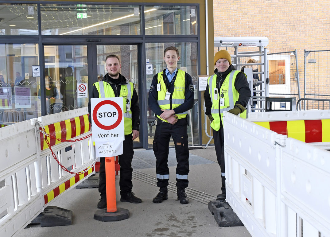 En gruppe mennesker med sikkerhetsvester som står ved siden av et skilt
