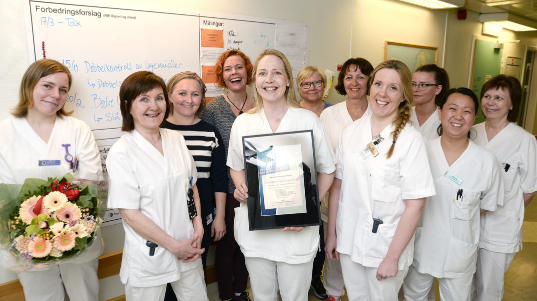 En gruppe kvinner i hvite laboratoriefrakker med et sertifikat