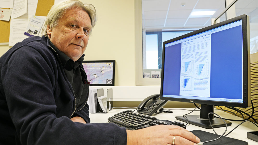 En mann som sitter ved et skrivebord med en datamaskin