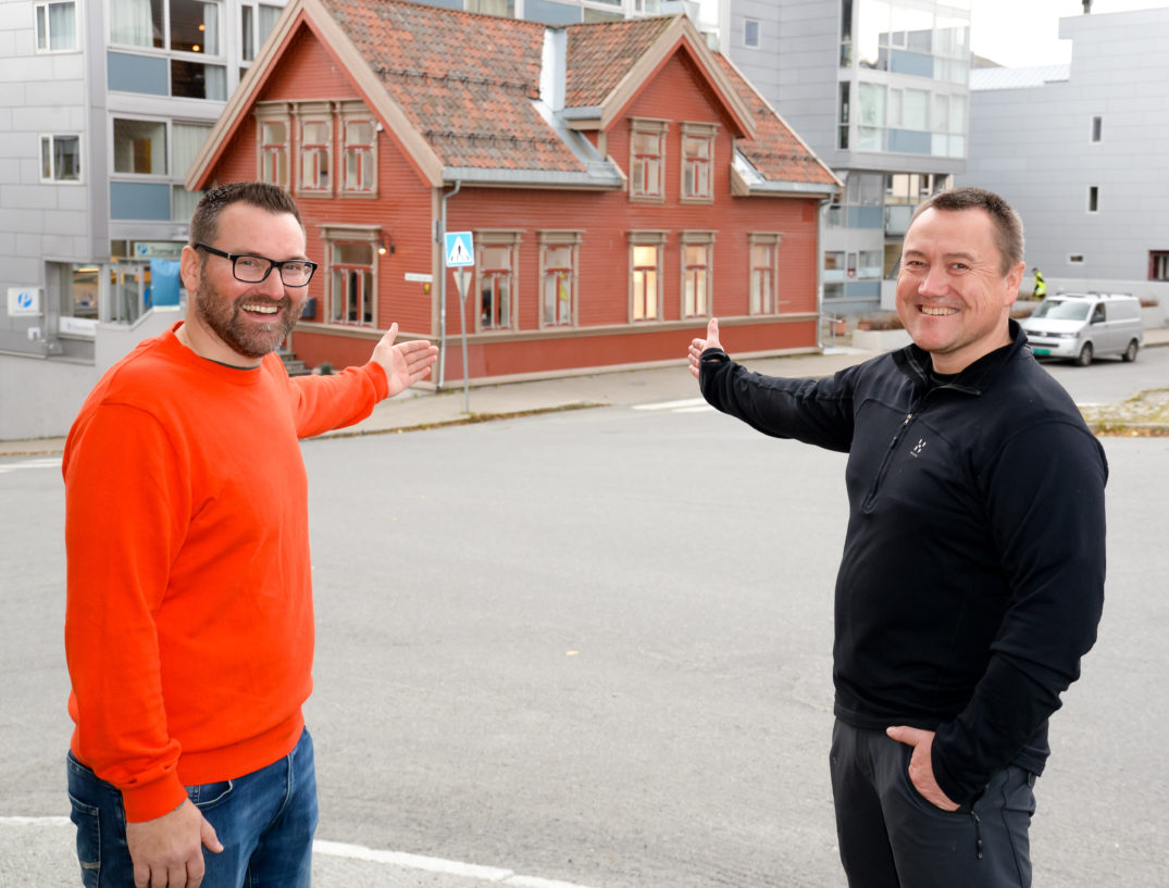 Et par menn som poserer for et bilde foran en bygning